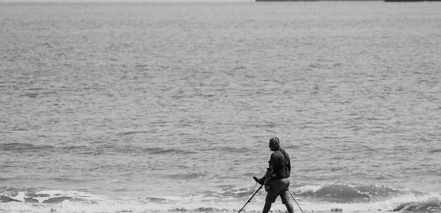 black and white photo of a man walking on a beach